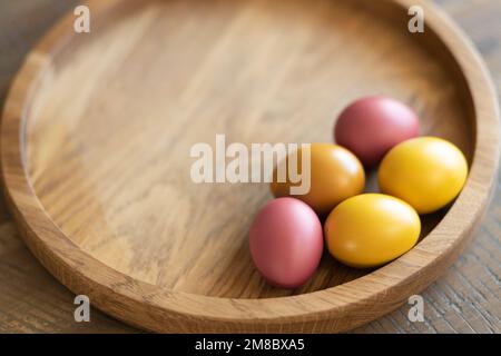 On a round wooden tray are five brightly colored Easter eggs and space for text. Stock Photo