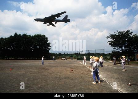 Japanese civilians pause during a game to watch a B-52G Stratofortress aircraft pass overhead. The 43rd Bombardment Wing aircraft flew to Japan from Andersen Air Force Base, Guam, for the annual Japanese-American Friendship Festival. Base: Yokota Air Base Country: Japan (JPN) Stock Photo