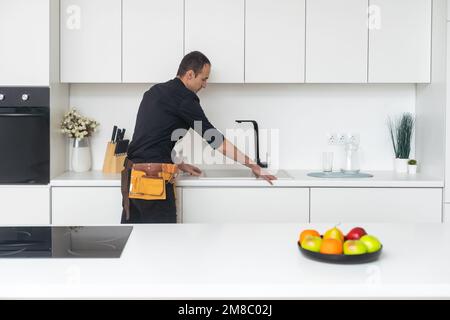 Young plumber repairing tap at kitchen Stock Photo
