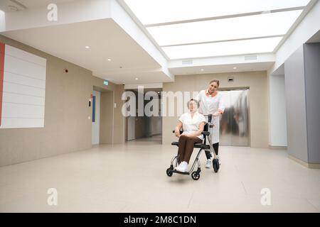 Kind woman is carrying an elderly woman in a wheelchair Stock Photo