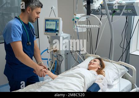 Female lies in intensive care, looking at nurse Stock Photo