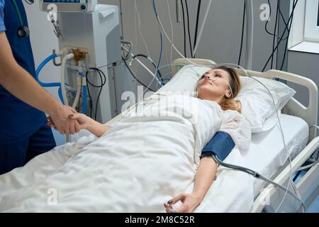 Pretty lady lies in intensive care, looking at nurse Stock Photo