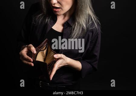 Unhappy bankrupt woman with empty wallet. Young woman shows her empty wallet. Bankruptcy. Stock Photo