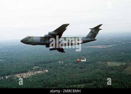 A Pilatus PC-9 aircraft, center foreground, flies beside a C-5A Galaxy ...