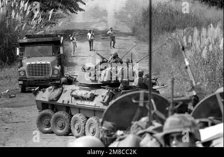 Armed Panamanian Defense Force soldiers wearing civilian clothes walk around a halted column of Marine Corps LAV25 light armored vehicles during Operation CHISUM, a route reconnaissance patrol. Supporters of General Manuel Noriega had blocked the road with vehicles and refused to allow the patrol from Company D, 2nd Light Armored Infantry Battalion, to proceed through the town. Subject Operation/Series: CHISUM Base: La Chorrera Country: Panama (PAN) Stock Photo