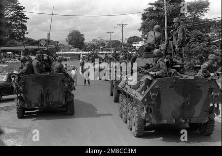 A flag-waving protester stands in the middle of a halted column of Marine Corps light armored vehicles on the edge of town during Operation CHISUM, a route reconnaissance patrol. Supporters of General Manuel Noriega had blocked the road with vehicles and refused to allow the patrol from Company D, 2nd Light Armored Infantry Battalion, to proceed through the town. Subject Operation/Series: CHISUM Base: La Chorrera Country: Panama (PAN) Stock Photo