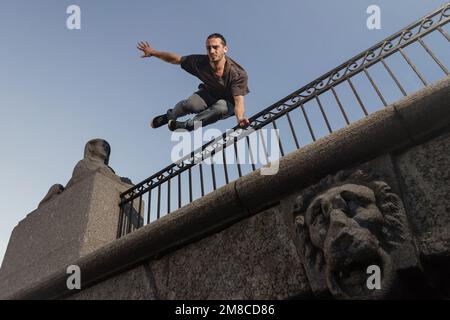 Man doing parkour in city. Athlete practicing freerunning, trick. Stock Photo