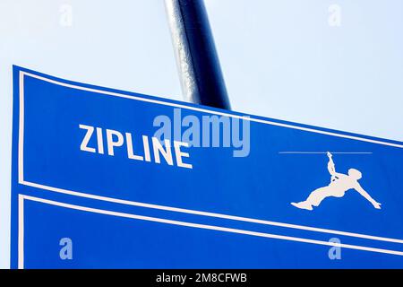 Blue and white extreme Zipline active sport sign on the board against the sky. Stock Photo