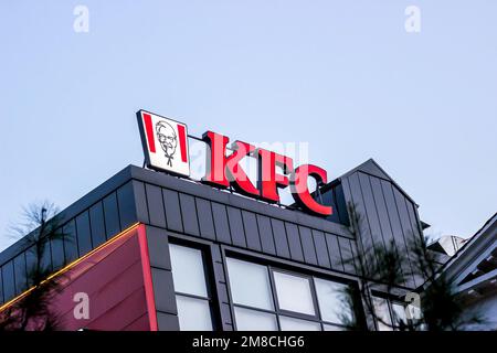 DUSHANBE, TAJIKISTAN - JULY 28, 2022: Red KFC fast food restaurant logo with Colonel Sanders against the blue sky. Stock Photo