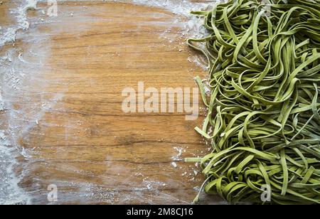 Fresh pasta. Homemade italian raw fettuccine pasta with spinach on wooden table background. High quality photo Stock Photo