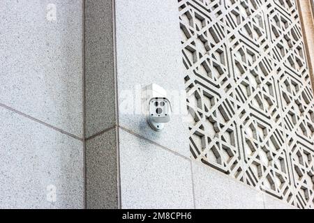 White CCTV security camera on the wall on the city street. Stock Photo