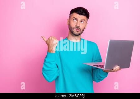 Photo of young minded thoughtful man programmer expert it developer hold laptop direct finger empty space isolated on pink color background Stock Photo
