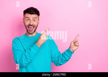 Photo of young crazy overjoyed student man brunet hair bristle beard point fingers empty space shock cheap prices isolated on pink color background Stock Photo