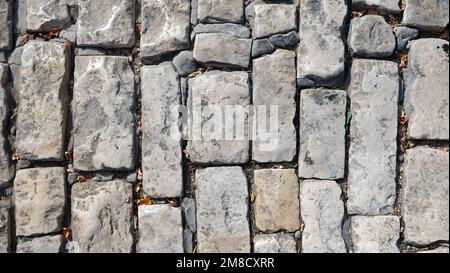 A Wall of old, cracked bricks or stones, with a Weathered Surface. Aged Brick Wall. Stock Photo