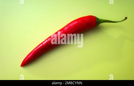 Fresh uncut red pepper on a green cutting board Stock Photo