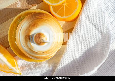 Top view of yellow lemon tart with meringue and fresh lemons on the kitchen table background with copy space. Stock Photo