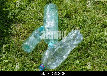 empty plastic bottles are lying on the green lawn Stock Photo