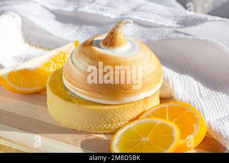 Yellow lemon tart with meringue and fresh lemons on the kitchen table background. Stock Photo