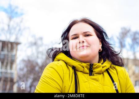 Happy attractive chubby overweight Caucasian woman smiling portrait outdoors. Cheerful pretty body positive person laughing during walk in the park. Stock Photo