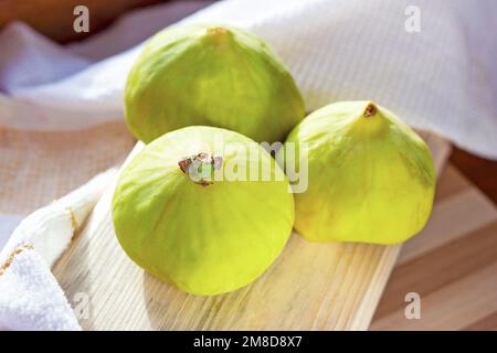 Fresh green fig fruit on the wooden board in the kitchen close up during the summer season. Stock Photo