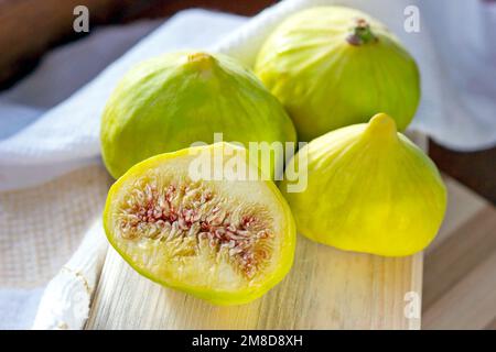 Fresh green fig fruit on the wooden board in the kitchen close up during the summer season. Stock Photo