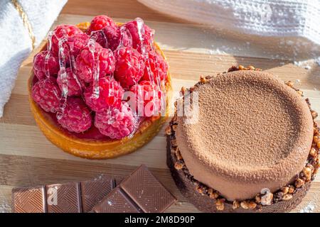 Top view of fresh raspberry and chocolate tarts on the kitchen table background close up. Stock Photo