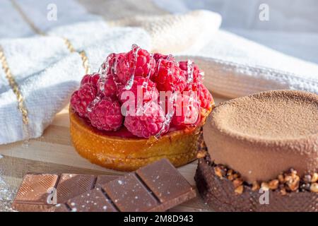 Fresh raspberry and chocolate tarts on the kitchen table background close up. Stock Photo