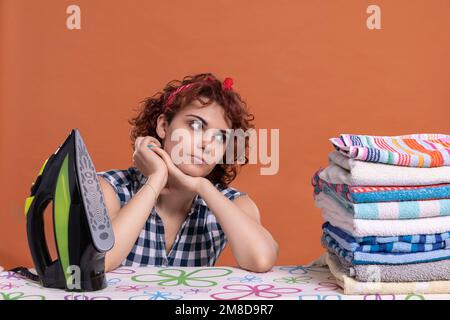 A young woman glances at a folded pile of ironed and fragrant towels. Stock Photo