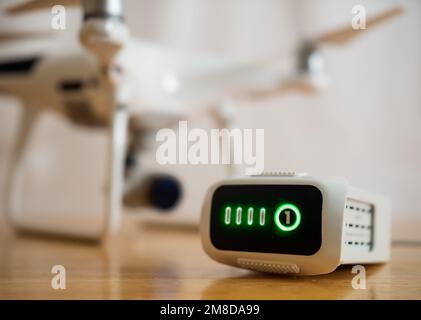 Drone intelligent lithium-polymer battery charging on wood desk with UAV aircraft in background. Stock Photo