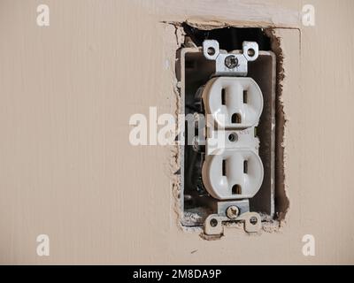 Residential electrical power outlet in need of repair.  Electricity power socket on painted wall. Stock Photo