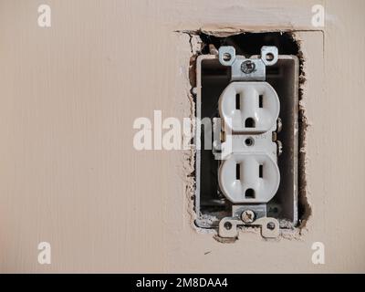 Residential electrical power outlet in need of repair.  Electricity power socket on painted wall. Stock Photo