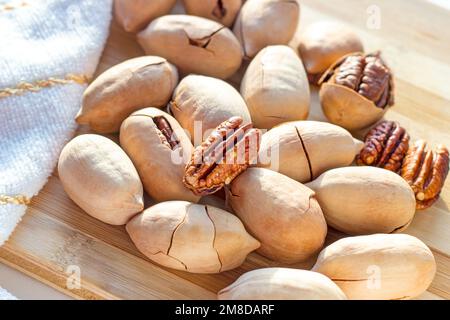 Many brown pecan nuts on light wooden background close up. Stock Photo