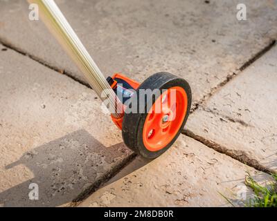 Measuring wheel tool for calculating distance. Outdoor surveying measurement tool with rolling odometer. Stock Photo
