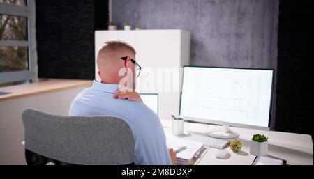 Posture Fatigue Shoulder Pain. Mature Man At Computer Workstation Stock Photo