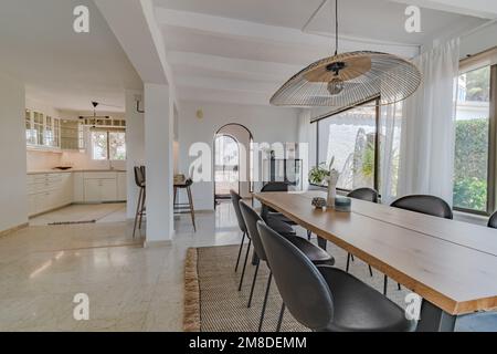 a long wooden dining table with open kitchen in the background at chalet Stock Photo