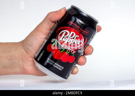 DUSHANBE, TAJIKISTAN - SEPTEMBER 11, 2022: Woman hands holding the black and red aluminium Dr. Pepper Cherry can close up on white background. Stock Photo