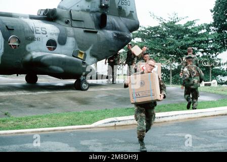 Marines unload boxes of supplies from a Marine Medium Helicopter Squadron 261 (HMM 261) CH-46E Sea Knight helicopter on the grounds of the US Embassy. Marines of the 22nd Marine Expeditionary Unit (22nd MEU), deployed aboard the amphibious assault ship USS SAIPAN (LHA 2), were sent to augment security at the embassy as part of Operation SHARP EDGE. Subject Operation/Series: SHARP EDGE Base: Monrovia Country: Liberia (LBR) Stock Photo