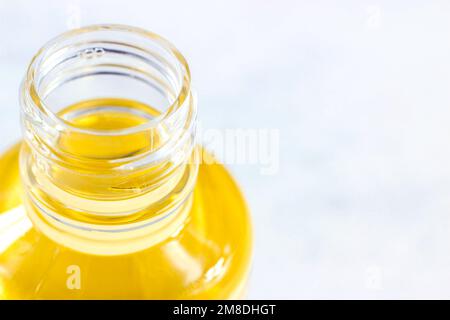 Bright yellow oil in plastic trasparent bottle on light background close up with copy space. Stock Photo