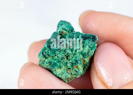 Woman hand holding green crystal Jasper on light background close up. Stock Photo