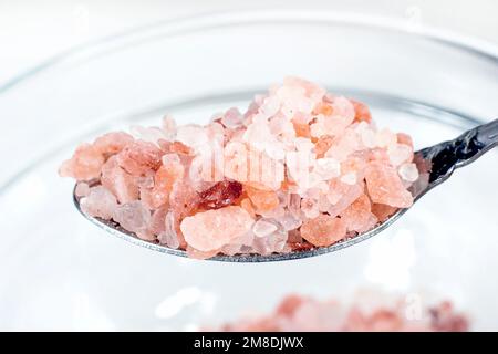 Pink Himalayan salt in the spoon on light background close up. Stock Photo