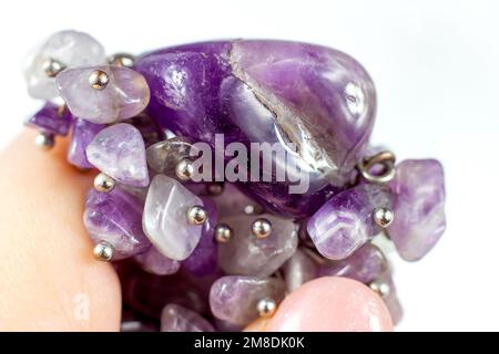 Bright transparent violet amethyst crystal gems in the hand on light background close up. Stock Photo