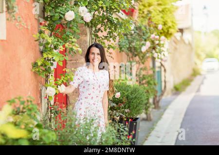 Young woman staying near red door on the street in old town Stock Photo