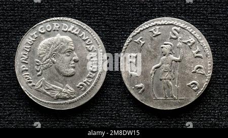Ancient Roman coin of emperor Gordian III. Old rare money, silver denarius isolated on dark background, macro. Concept of Rome, empire, valuable coin, Stock Photo