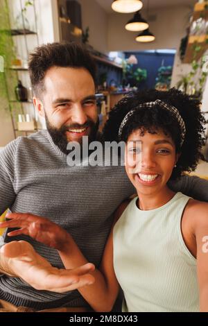 Portrait of cheerful biracial young couple smiling while relaxing on sofa in living room Stock Photo