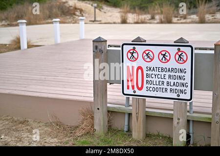 A sign informs the public of no skateboarding, bicycle riding, roller blading, or scooter riding. Stock Photo