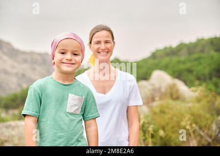 Child in nature with his nurse. The child is wearing a pink scarf on his head. Stock Photo