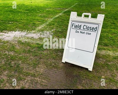 Field Closed Do Not Use sign on green lawn at a public park due to weather conditions. Stock Photo