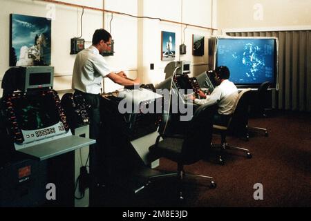 A technician replaces a printed circuit board in a display console for an AN/SPQ-12(V) radar system as another technician monitors an operational console. The two are working at the radar test range as part of the Naval Research Laboratory (NRL) Chesapeake Bay Detachment. Country: Unknown Stock Photo