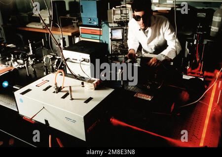 A technician at the Naval Research Laboratory (NRL) monitors the operation of a dye laser in the Fiber Optics Laser Facility. The dye laser, which is activated by the green laser at left, is used to measure the properties of fiber optics. Base: Washington State: District Of Columbia (DC) Country: United States Of America (USA) Stock Photo