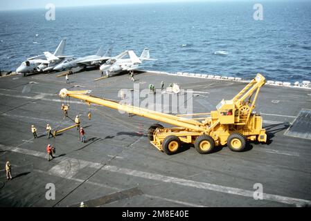 A carrier vessel crash crane is being brought onto the flight deck of ...